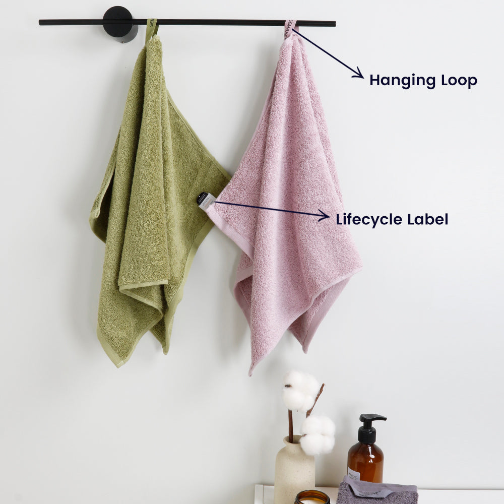 Green and purple hand towels hang from towel rails, revealing their unique hanging loop and lifecycle label design