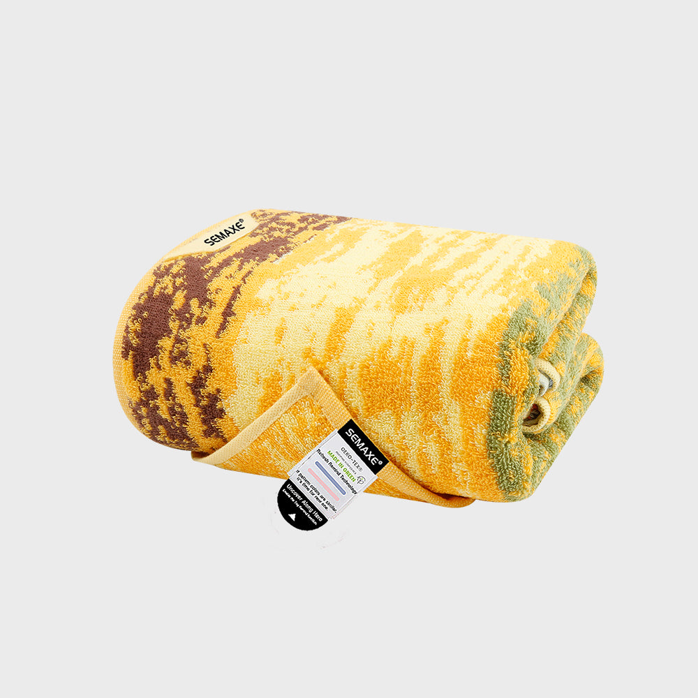 This SEMAXE Wheat Field Bath Towel features a vibrant, golden yellow color with rustic brown accents, reminiscent of a rippling wheat field under the summer sun. Crafted from premium 100% cotton, it offers luxurious softness and superior absorbency, making it a perfect blend of style and functionality for your bathroom essentials.