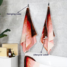 Two bath towels from the "Plum Garden" collection are hung on the bathroom wall with unique loops and lifecycle labels.