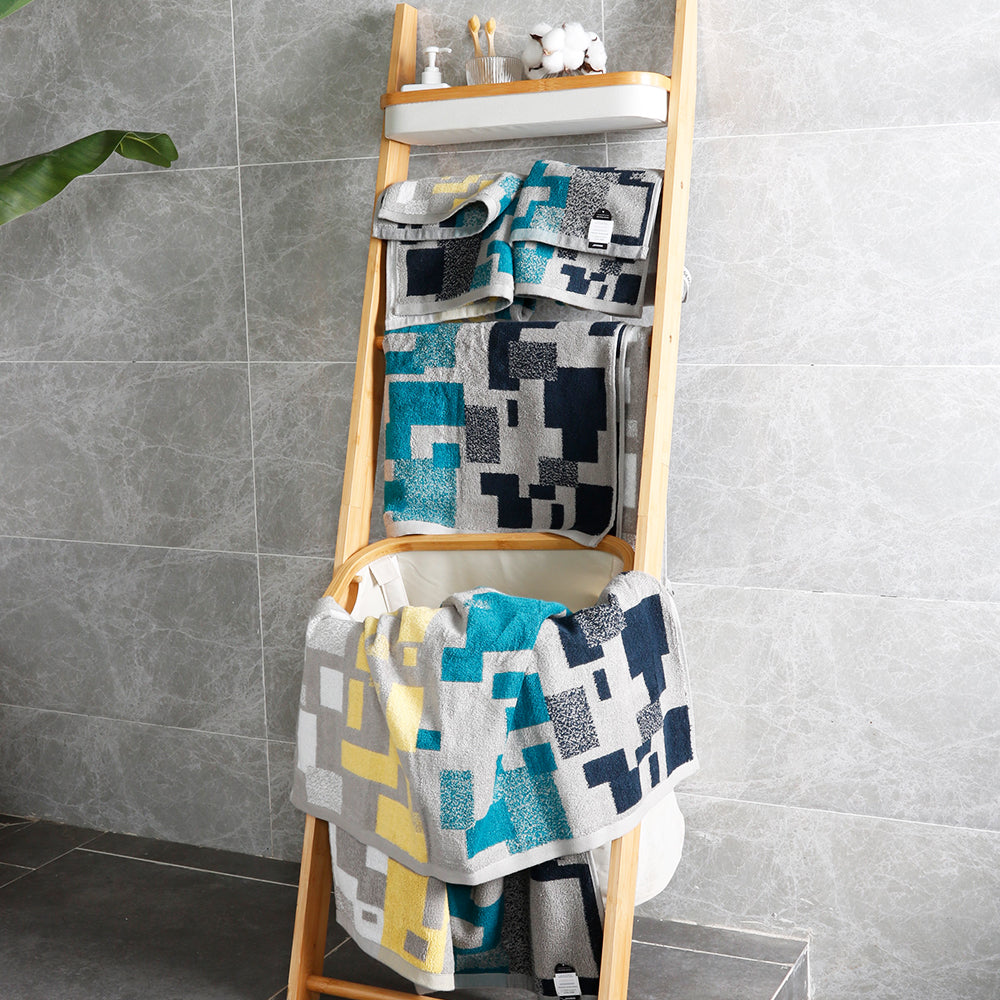 The Impression towel set hangs on a shelf in the bathroom, revealing its geometric pattern in rich colours
