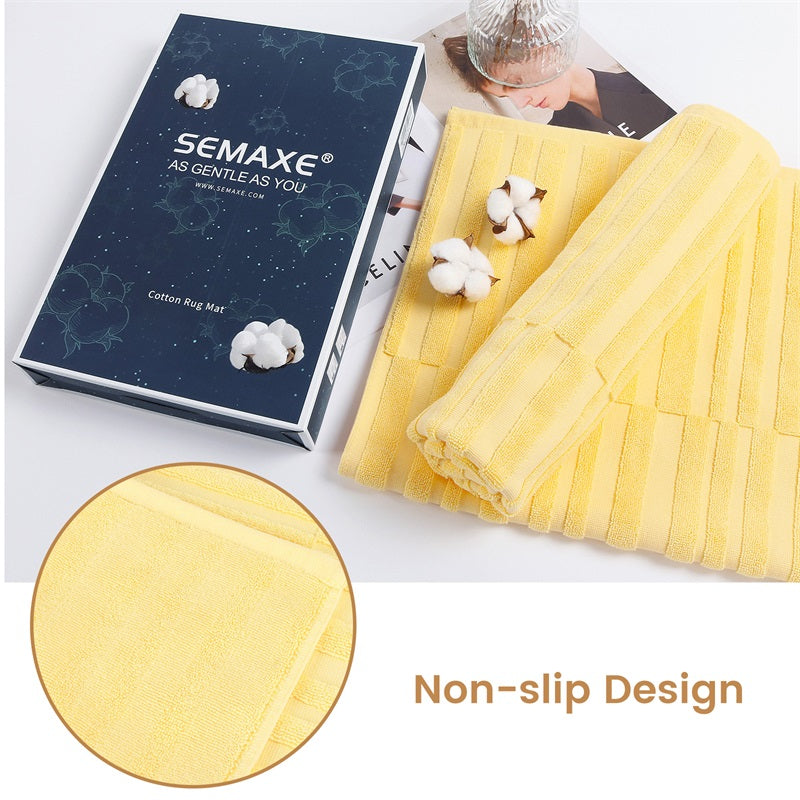 "SEMAXE gift box featuring yellow non-slip bath mats, elegantly packaged with a focus on high-quality cotton material, showcased alongside cotton buds and a product booklet, ideal for enhancing bathroom aesthetics.