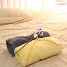 The yellow + gray towel is folded like a flat and placed on the bed