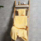 There is a shelf full of yellow towels in a modern bathroom