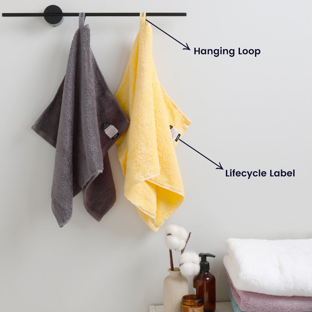 Yellow and grey towels hang neatly on towel rails and are showcasing its unique loops and lifecycle labels