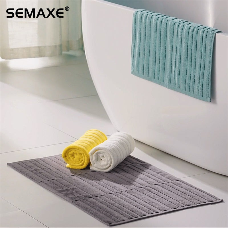 SEMAXE bath mat series displayed in a modern bathroom setting, featuring mats in four colors including gray, white, yellow, and blue, neatly rolled up for an elegant presentation-all-groups