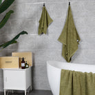 Green hand towels and bath towels hang on the walls of modern bathrooms while showing off their gift box packaging