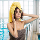 A girl wearing a yellow towel wrapped around her head and smiling in a gray pool towel -all groups